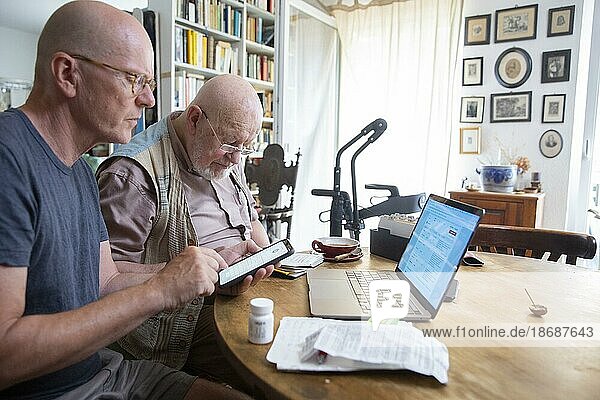 Digitale Welt im Alter. Vater und Sohn mit Handy und Laptop.  Heidelberg  Deutschland  Thema  Europa