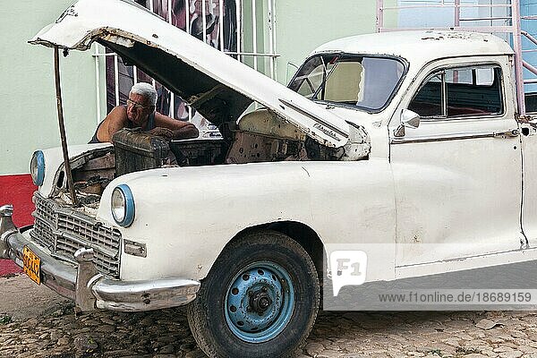 Kubanischer Automechaniker repariert einen amerikanischen Chrysler Pickup aus den 1950er Jahren auf der Straße in Trinidad  Kuba  Karibik  Mittelamerika