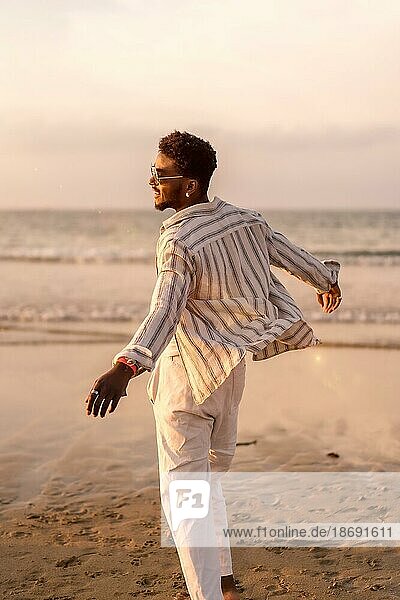 Portrait of attractive black ethnic man enjoying summer vacation by the sea feeling free and dancing