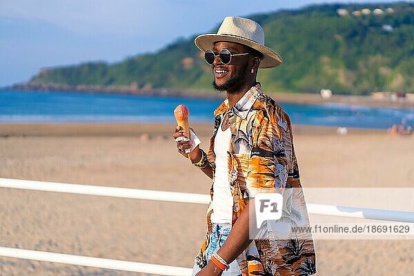 Schwarzer ethnischer Mann genießt Sommerurlaub am Strand und isst Eiscreme