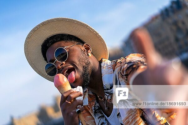 Schwarzer ethnischer Mann genießt Sommerurlaub am Strand  isst ein Eis und macht ein Selfie