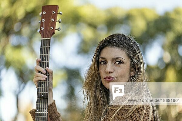 Junge blonde Frau mit ihrer Gitarre im Park. Konzept der kreativen Hobbys und Profis. Positive Einstellung. Ermächtigung