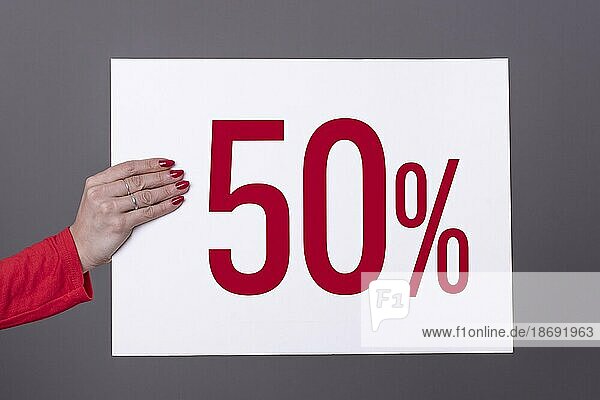 Weibliche Hand hält ein 50% Plakat. Studioaufnahme. Werbekonzept