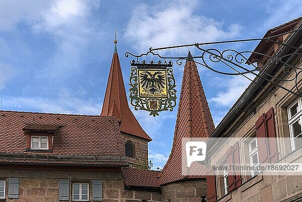 Nasenschild vom Gasthaus Schwarzer Adler  hinten die Wehrkirche St. Georg  Kraftshof  Mittelfranken  Bayern  Deutschland  Europa