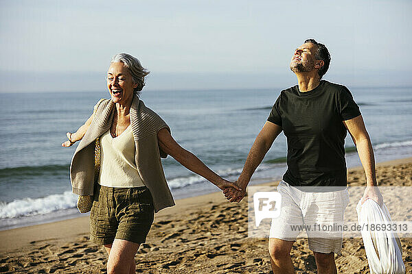 Carefree mature couple holding hands at beach