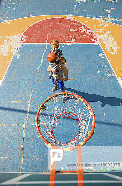 Sohn und Vater spielen Basketball auf dem Sportplatz