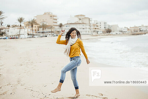 Happy woman dancing on coastline at beach