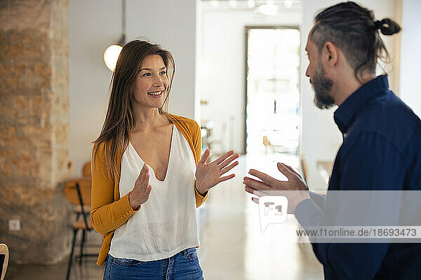 Smiling woman gesturing and talking to man at cafe