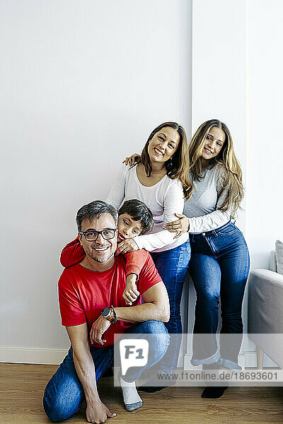 Father crouching by family near wall at home