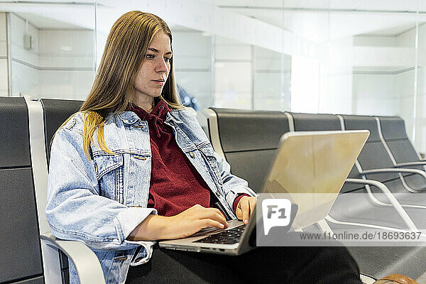Junge Frau benutzt Laptop in der Flughafenlobby