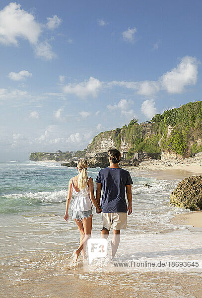 Paar hält Händchen und geht am Strand spazieren