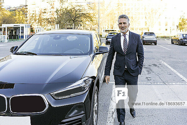 Mature businessman wearing suit walking next to car