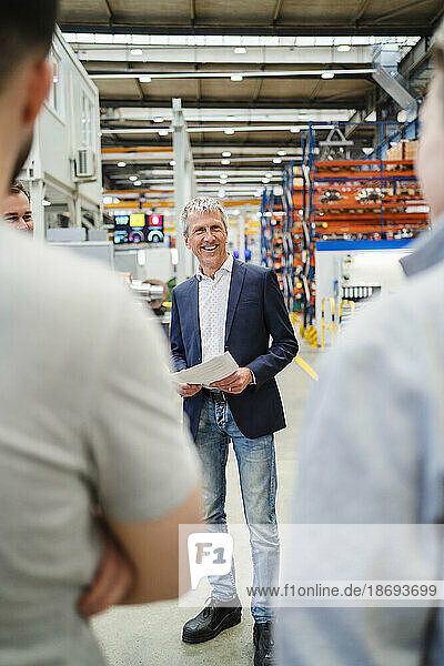 Happy businessman discussing with employees at factory