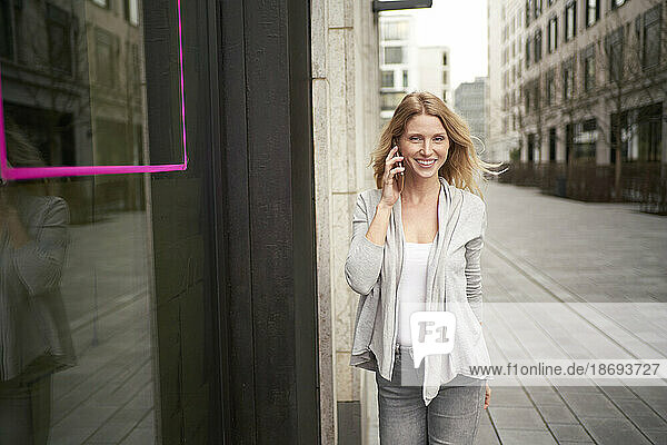 Smiling woman talking on mobile phone at sidewalk