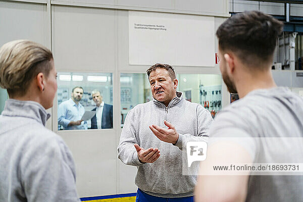 Employee gesturing and discussing with colleagues at factory