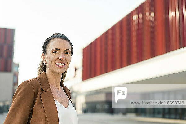 Lächelnde Geschäftsfrau vor modernem Gebäude