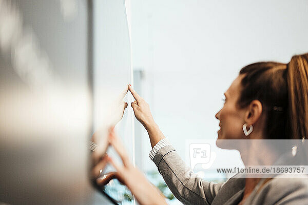 Junge Geschäftsfrau nutzt Touchscreen-Display im Büro