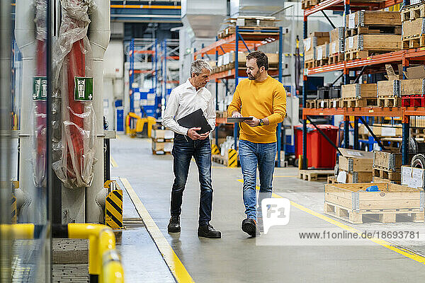 Manager and businessman walking together in production hall at factory