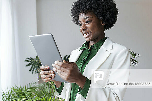 Happy young businesswoman using tablet PC at office