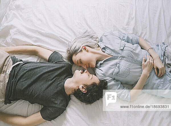 Loving couple lying on bed at home