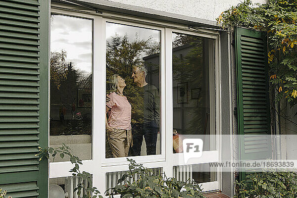 Senior couple behind windowpane of their home
