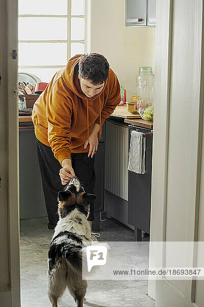 Nicht-binäre Person füttert Hund in der heimischen Küche