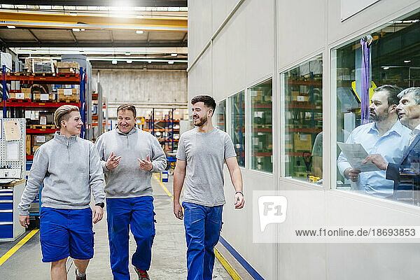Employees discussing and walking in production hall at factory