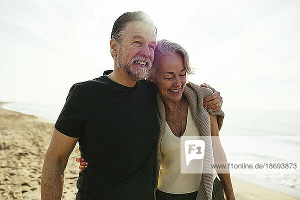 Happy man with arm around woman at beach