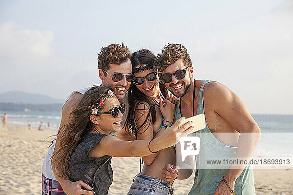 Happy woman taking selfie with friends on vacation at beach