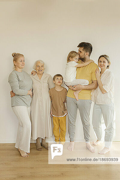 Glückliche Mehrgenerationenfamilie  die zu Hause gemeinsam vor der Wand steht