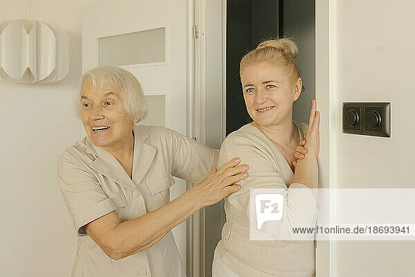 Ältere Frau steht zu Hause neben ihrer Tochter in der Nähe der Tür
