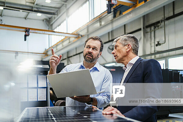 Manager pointing by businessman discussing at factory
