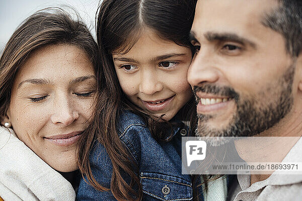 Smiling man with woman and daughter at beach