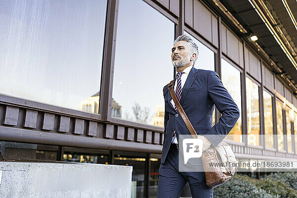 Businessman with bag walking by building
