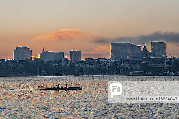 Germany  Hamburg  Alster Lake at dawn with city skyline and rowing boat in background