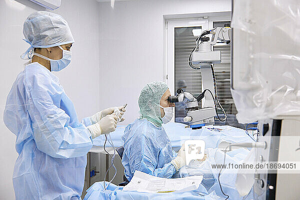 Nurse with surgeon performing eye surgery in operating room