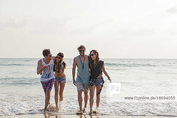 Glückliche Freunde  die am Strand im Wasser spazieren gehen