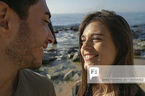 Happy young woman looking at man on sunny day