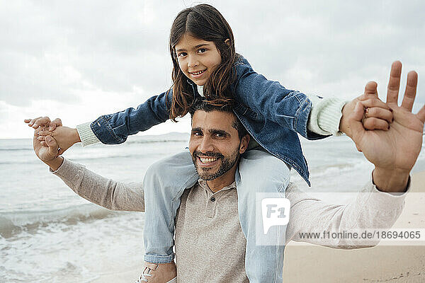 Happy man carrying daughter at beach