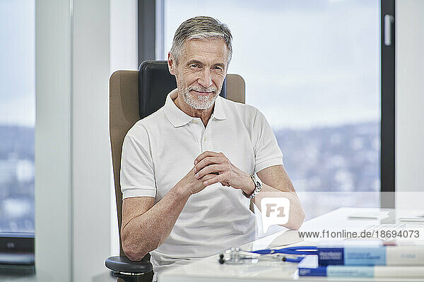 Portrait of confident doctor sitting at desk in medical practice