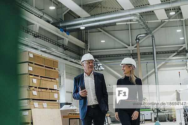 Senior businessman discussing with smiling colleague in carpentry factory