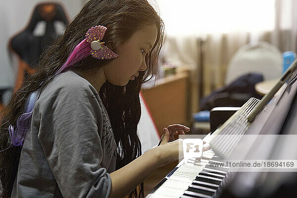 Girl with long hair learning to play piano
