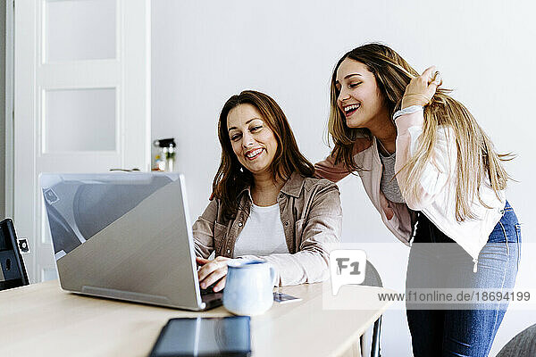 Mother and daughter watching video on laptop at home