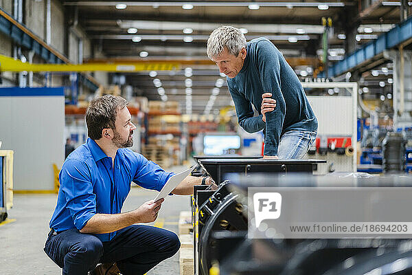 Manager discussing with manager over machinery at factory