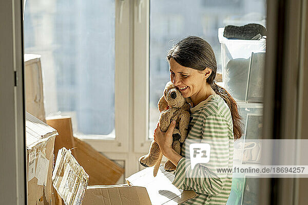 Woman embracing stuffed toy at home