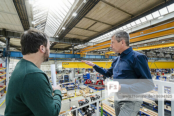 Businessman explaining colleague in factory