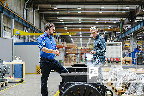 Businessman discussing with manager by machinery at factory