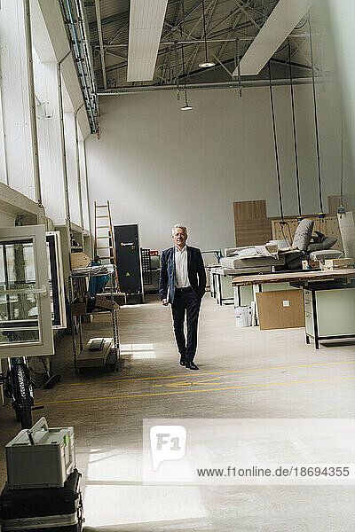 Senior businessman walking on production floor in factory