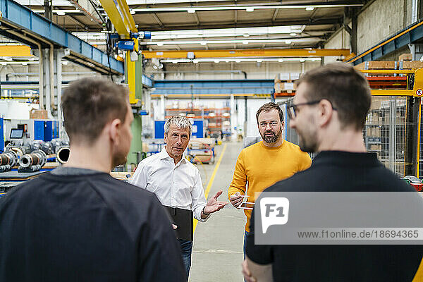 Businessman explaining to employees in meeting at factory