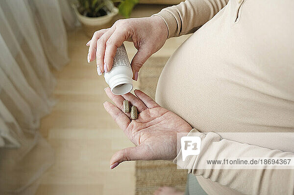 Pregnant woman taking vitamin pills at home